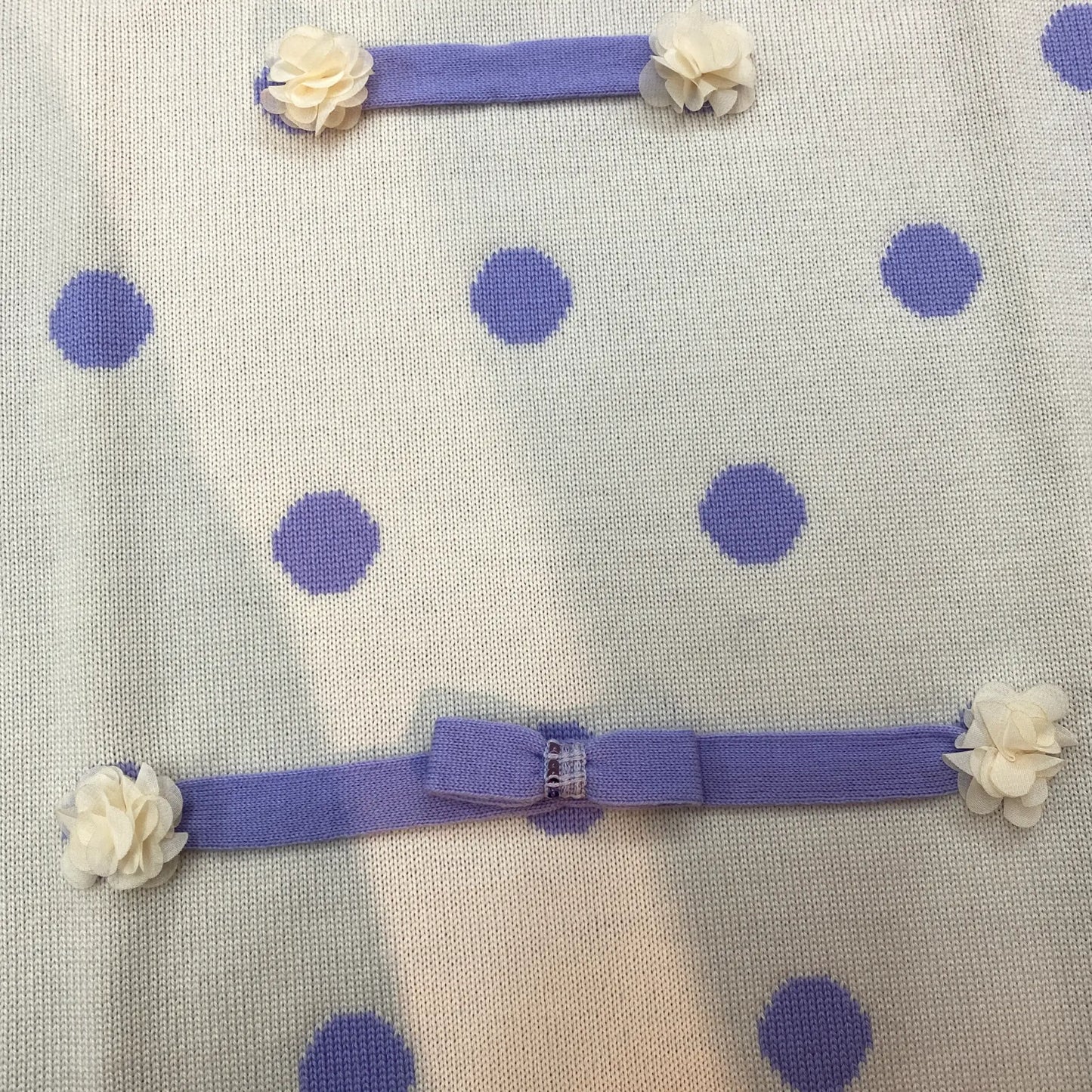 Dettaglio delle applicazioni sulla copetina da neonata in maglia doppiata